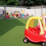 Outdoor play area at Little Tykes with artificial turf and age-appropriate playground toys.