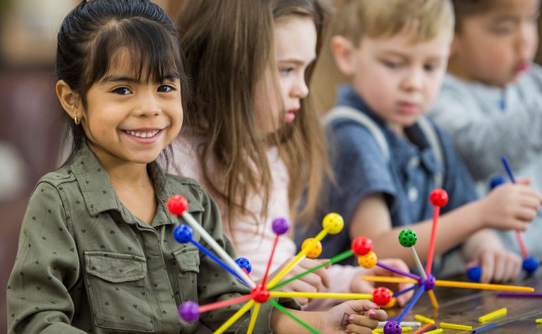 Young children building with colorful educational toys during classroom activity.