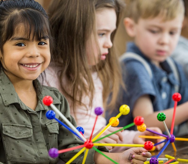Young children building with colorful educational toys during classroom activity.
